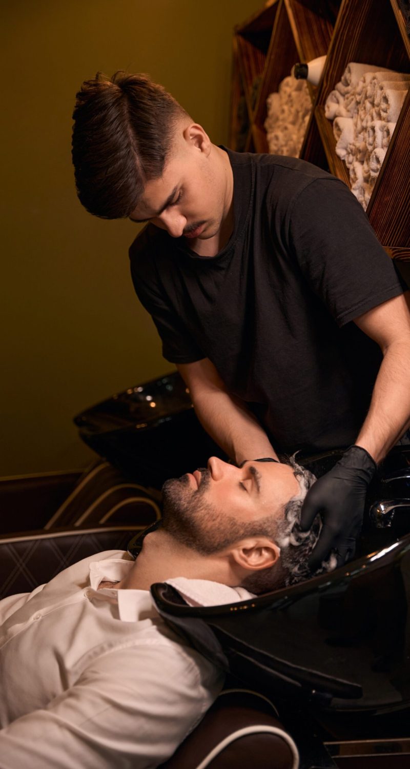hairdresser-man-washing-client-head-with-shampoo-CMU56AW-scaled.jpg